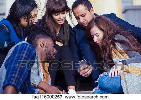 Friends sitting on steps and using smartphone View Large Photo Image Stock Photo - Friends sitting on steps and using smartphone. Fotosearch