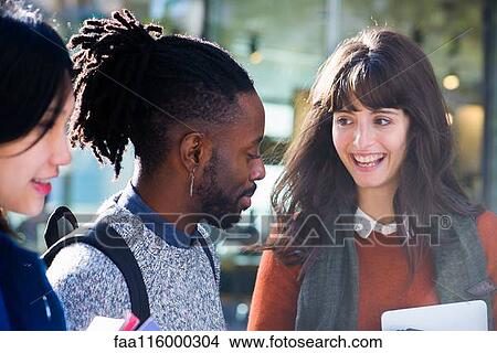 Friends standing together and holding digital tablet View Large Photo Image Picture - Friends standing together and holding digital tablet. Fotosearch