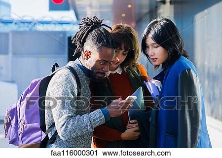 Friends standing together and using smartphone View Large Photo Image Stock Image - Friends standing together and using smartphone. Fotosearch