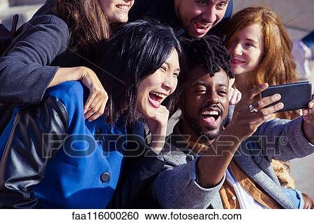 Stock Image - Friends taking selfie with smartphone. Fotosearch