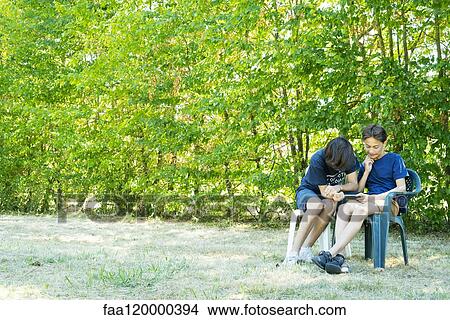Friends using smart phone in park View Large Photo Image Picture - Friends using smart phone in park. Fotosearch