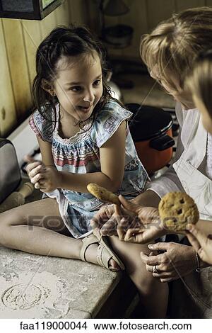 Picture - Girl with her mother and grandmother sitting in kitchen. Fotosearch