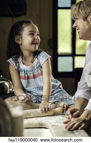 Stock Image - Granddaughter and grandmother preparing food. Fotosearch