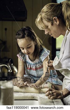 Stock Image - Granddaughter and grandmother preparing food. Fotosearch