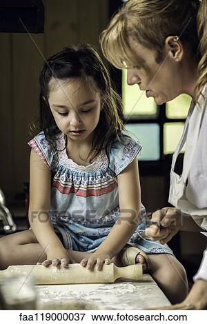 Stock Photo - Granddaughter and grandmother preparing food. Fotosearch