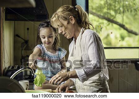 Stock Image - Grandmother and granddaughter preparing food. Fotosearch