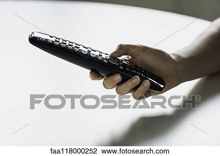 Stock Image - Hand holding remote control. Fotosearch