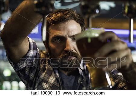 Stock Image - Man drawing beer from tap. Fotosearch