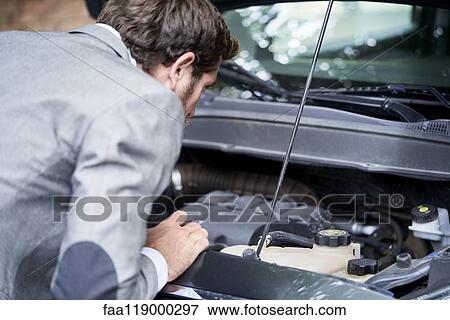 Man examining car engine View Large Photo Image Stock Photo - Man examining car engine. Fotosearch