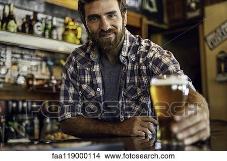 Man holding beer glass at counter View Large Photo Image Picture - Man holding beer glass at counter. Fotosearch