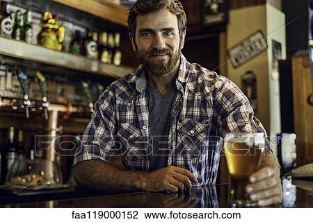 Man holding beer glass at counter View Large Photo Image Stock Image - Man holding beer glass at counter. Fotosearch