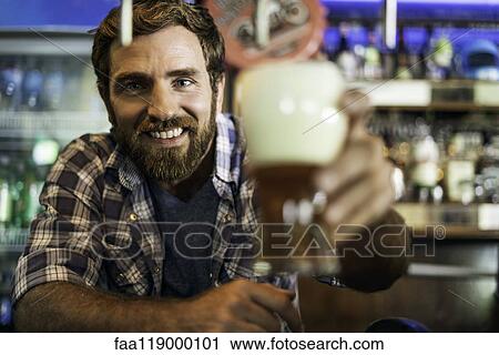 Stock Image - Man holding beer glass. Fotosearch