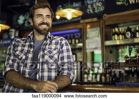 Picture - Man leaning against bar counter. Fotosearch
