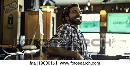 Stock Image - Man leaning against bar counter. Fotosearch