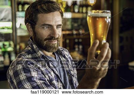 Man looking at beer glass View Large Photo Image Stock Image - Man looking at beer glass. Fotosearch