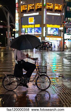 Man riding a bicycle on rainy night View Large Photo Image Stock Photo - Man riding a bicycle on rainy night. Fotosearch