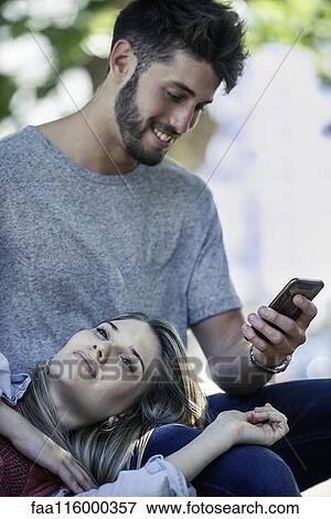 Man using a smartphone while woman relaxing on his lap View Large Photo Image Stock Photo - Man using a smartphone while woman relaxing on his lap. Fotosearch