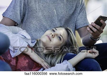 Man using a smartphone while woman relaxing on his lap View Large Photo Image Stock Photograph - Man using a smartphone while woman relaxing on his lap. Fotosearch