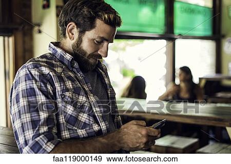 Stock Photo - Man using smartphone in bar. Fotosearch