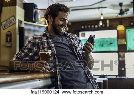 Man using smartphone in beer bar View Large Photo Image Picture - Man using smartphone in beer bar. Fotosearch