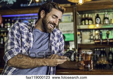 Man using smartphone in beer bar View Large Photo Image Stock Image - Man using smartphone in beer bar. Fotosearch