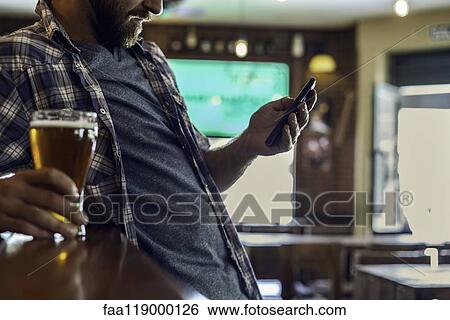 Man using smartphone in beer bar View Large Photo Image Stock Photograph - Man using smartphone in beer bar. Fotosearch