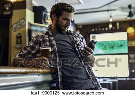 Man using smartphone in beer bar View Large Photo Image Stock Photography - Man using smartphone in beer bar. Fotosearch