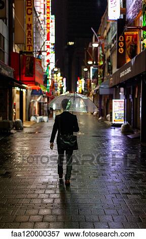 Man walking in rain with umbrella at night View Large Photo Image Stock Photo - Man walking in rain with umbrella at night. Fotosearch