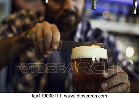 Man with a knife removing froth from a beer glass View Large Photo Image Stock Image - Man with a knife removing froth from a beer glass. Fotosearch