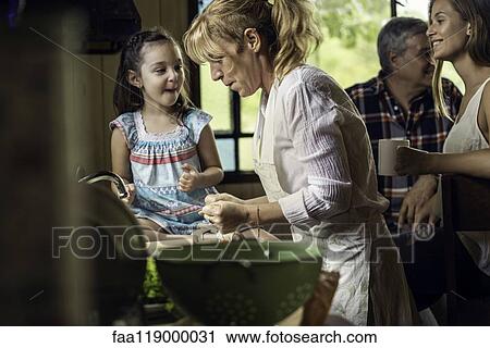 Stock Image - Mature woman cooking with her granddaughter in kitchen. Fotosearch