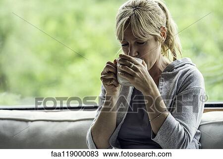 Stock Image - Mature woman having coffee at home. Fotosearch