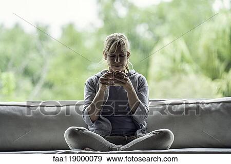 Stock Photo - Mature woman having coffee at home. Fotosearch