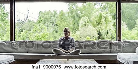 Stock Photograph - Mature woman sitting on sofa. Fotosearch
