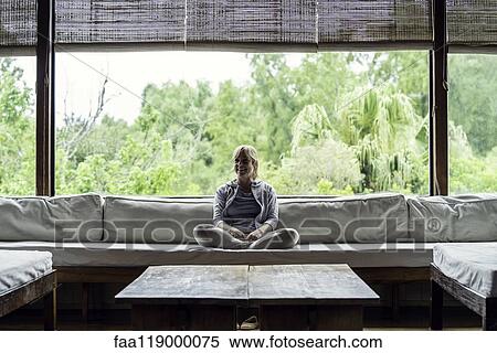 Stock Photography - Mature woman sitting on sofa. Fotosearch