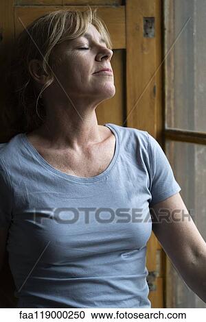 Mature woman standing near window View Large Photo Image Stock Image - Mature woman standing near window. Fotosearch