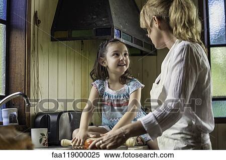 Stock Photography - Mature woman talking with her granddaughter in kitchen. Fotosearch