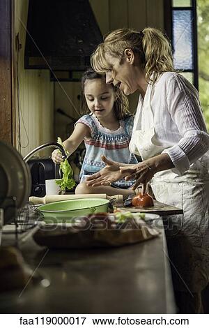 Stock Photo - Mature woman teaching her granddaughter in kitchen. Fotosearch