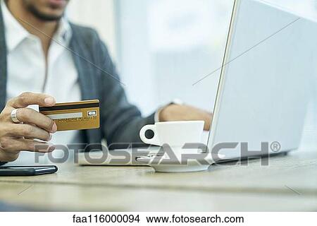 Picture - Mid section of businessman holding credit card. Fotosearch