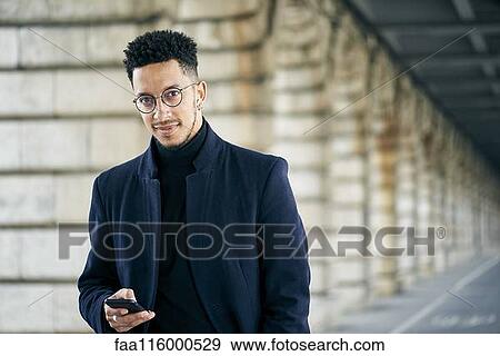 Stock Photo - Portrait of businessman holding smartphone. Fotosearch