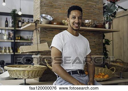 Stock Photograph - Portrait of man sitting in shop. Fotosearch