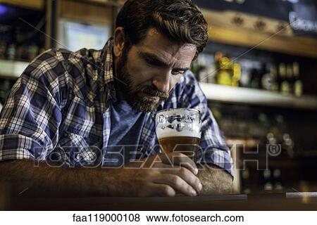 Stock Photo - Sad man sitting in beer bar. Fotosearch