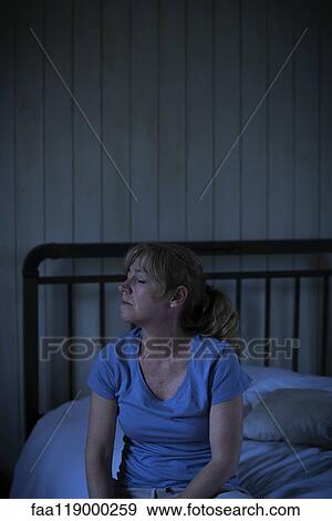 Stock Photo - Sad mature woman sitting on bed. Fotosearch