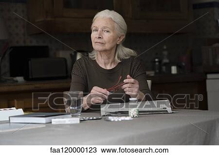Stock Image - Senior woman sitting at home. Fotosearch