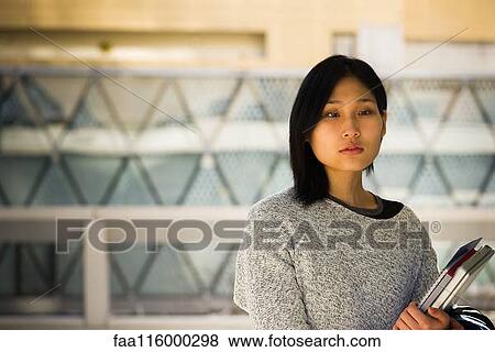 Serious woman holding laptop and file View Large Photo Image Stock Photo - Serious woman holding laptop and file. Fotosearch