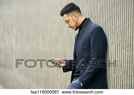 Stock Photo - Side view of businessman using smartphone. Fotosearch