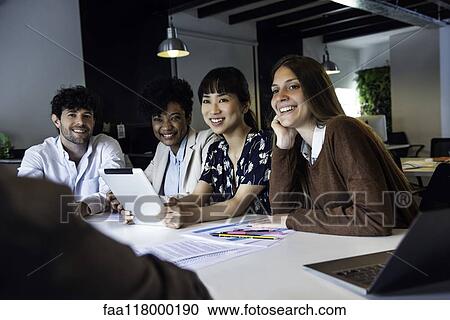Stock Image - Smiling business people sitting in office. Fotosearch