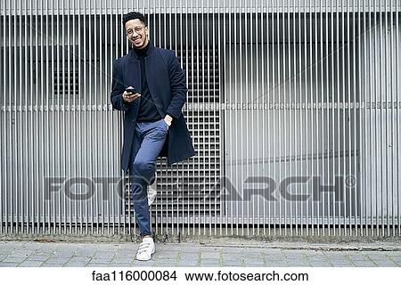 Picture - Smiling businessman holding smartphone. Fotosearch