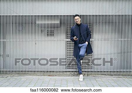 Stock Image - Smiling businessman holding smartphone. Fotosearch