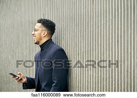 Smiling businessman holding smartphone View Large Photo Image Stock Photo - Smiling businessman holding smartphone. Fotosearch