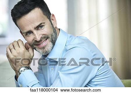 Smiling businessman sitting in hotel lobby View Large Photo Image Picture - Smiling businessman sitting in hotel lobby. Fotosearch